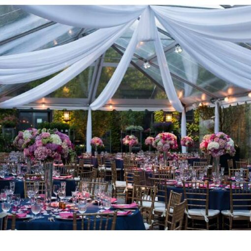Pin-Spots under a clear-top tent highlight the floral centerpiece at each table for a wedding at The Foundry.