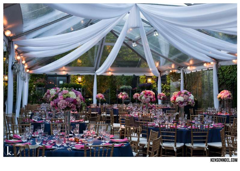 Pin-Spots under a clear-top tent highlight the floral centerpiece at each table for a wedding at The Foundry.