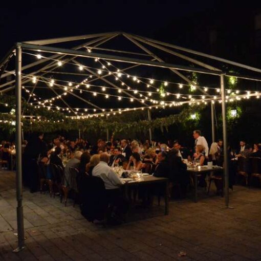 Warm White String Light hanging under a raw tent frame for a wedding in the courtyard at The Foundry.