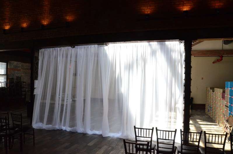 White Sheer Curtains hanging as a backdrop behind ceremony area for a wedding at 26 Bridge.