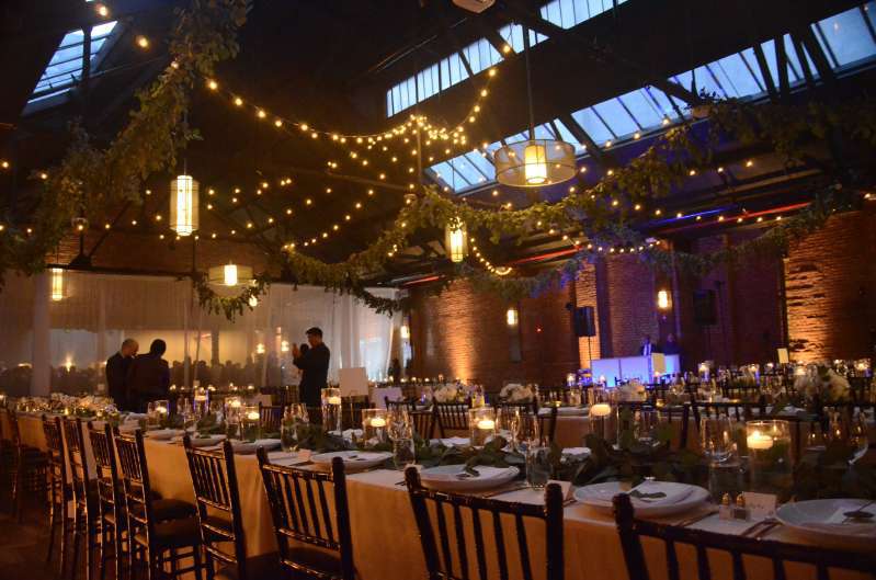 Warm White String Lights hanging overhead in a circular pattern with up-lights against the perimeter walls for a wedding at 26 Bridge.
