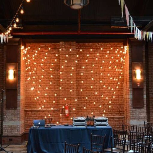 A backdrop of String light hanging with multiple horizontal swoops behind against a wall at 26 Bridge.
