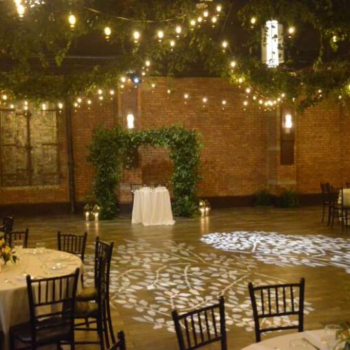 Warm White String Lights hanging in a zigzagging pattern for a wedding in the main room at 26 Bridge. A stock Gobo image illuminates the dance floor.
