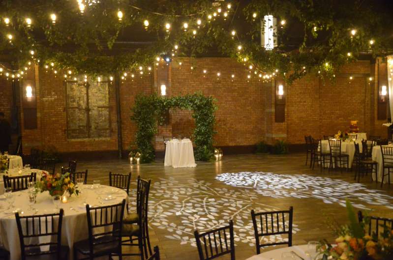 Warm White String Lights hanging in a zigzagging pattern for a wedding in the main room at 26 Bridge. A stock Gobo image illuminates the dance floor.
