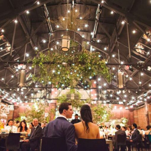 String Lights hanging overhead in parallel lines and swoop upward toward the peek of the center ceiling for a wedding at 26 Bridge.