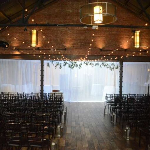 String Lights with round G50 Bulbs are hanging in a V-shaped pattern between the 3rd and 5th Beams in the Main Room for a wedding at 26 Bridge.