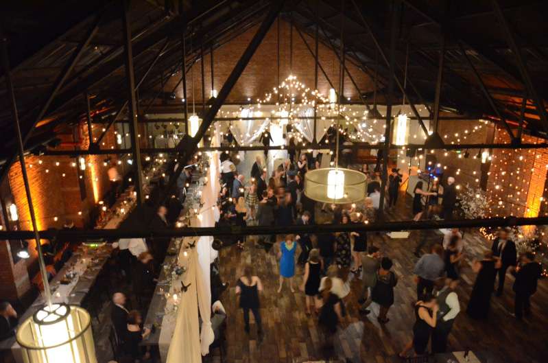 String Lights are hanging in two circular/star-shaped patterns with round clear G50 bulbs between the 1st and 4th beams.  String Lights are hanging vertically with round white G50 Bulbs as a backdrop behind the ceremony area. Amber Up-Lights around the perimeter of the main room.