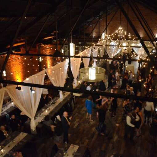 String Lights are hanging in two circular/star-shaped patterns with round clear G50 bulbs between the 1st and 4th beams.  String Lights are hanging vertically with round white G50 Bulbs as a backdrop behind the ceremony area. Amber Up-Lights around the perimeter of the main room.
