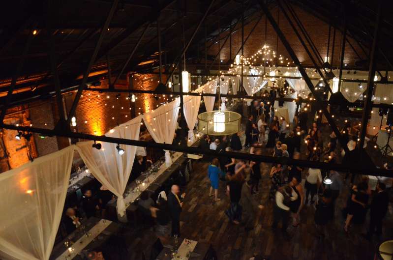 String Lights are hanging in two circular/star-shaped patterns with round clear G50 bulbs between the 1st and 4th beams.  String Lights are hanging vertically with round white G50 Bulbs as a backdrop behind the ceremony area. Amber Up-Lights around the perimeter of the main room.