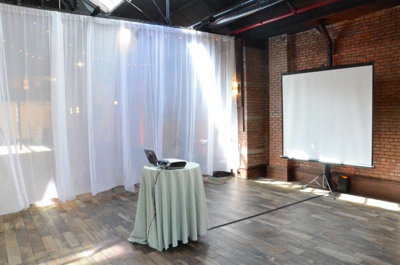 A projector and tripod-base screen for a video montage during a wedding at 26 Bridge.