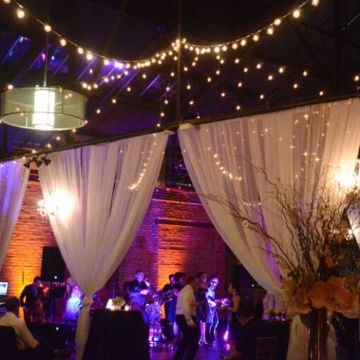 String Lights with round G50 bulbs hanging in two circular/star shape above the main floor at 26 Bridge. Also, chandeliers hanging in the rear bar area.