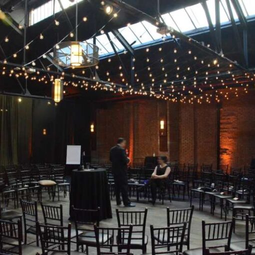 A canopy of string lights with round G50 bulbs hanging between 2nd and 3rd beam that cross the width of the main room at 26 Bridge.  Also, Amber Up-Lights around the perimeter of the main room.