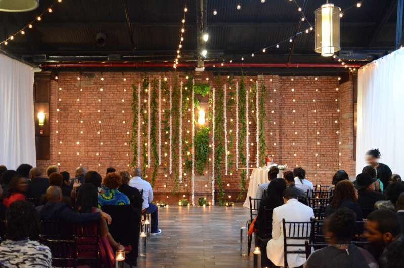 String Lights hanging vertically as a backdrop behind the ceremony at 26 Bridge. Along with String Lights hanging in two circular/star shape patterns above the main room at 26 Bridge.