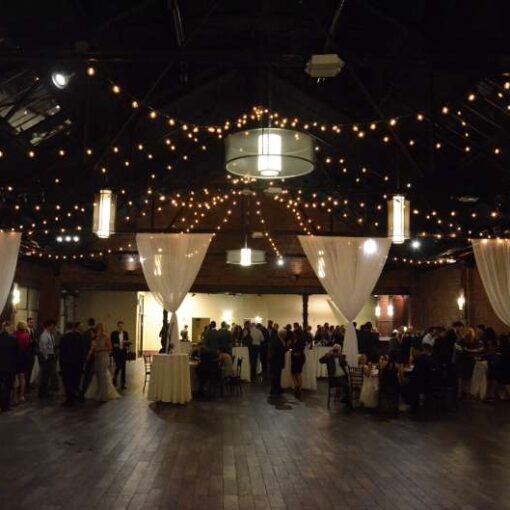 String Lights hanging in a two Circular/Star star shaped patterns over the main room for a wedding at 26 Bridge.