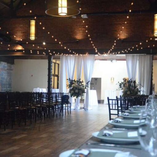 String Lights with round G50 Bulbs are hanging in a V-shaped pattern between the 3rd and 5th Beams in the Main Room for a wedding at 26 Bridge.