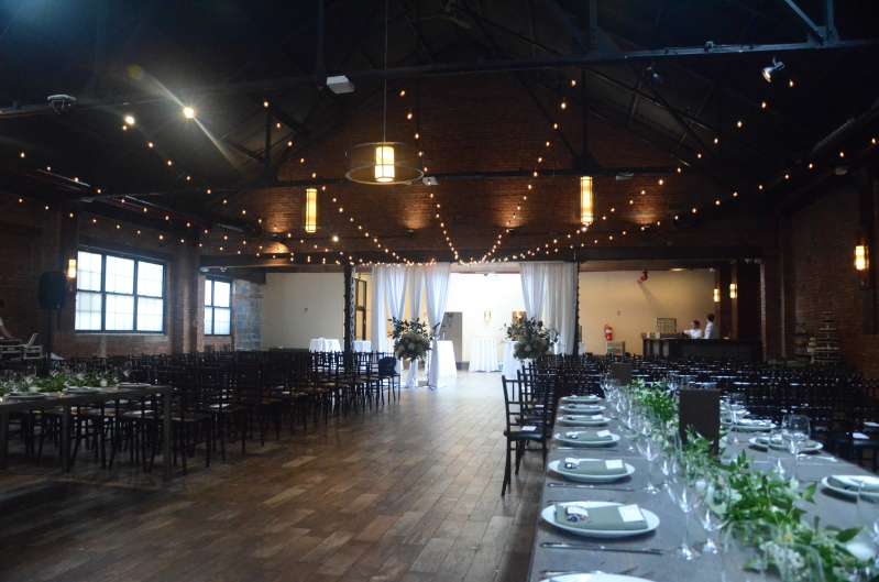 String Lights with round G50 Bulbs are hanging in a V-shaped pattern between the 3rd and 5th Beams in the Main Room for a wedding at 26 Bridge.