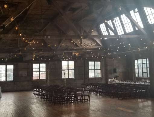 Warm White String Lights hanging in a zigzagging pattern between the six center columns for a wedding in the main room at The Greenpoint Loft.