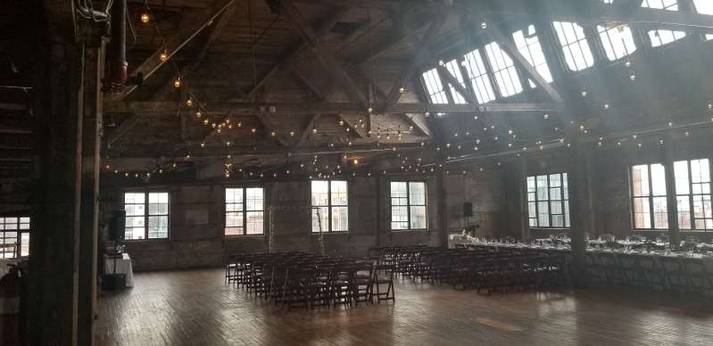 Warm White String Lights hanging in a zigzagging pattern between the six center columns for a wedding in the main room at The Greenpoint Loft.
