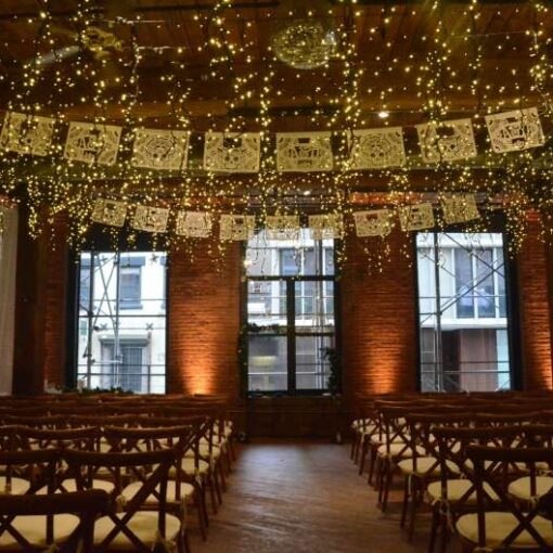Fairy (Icicle) Lights hanging between the center columns for a wedding at The Dumbo Loft. Also, Up-Lights at the base of each column between windows.