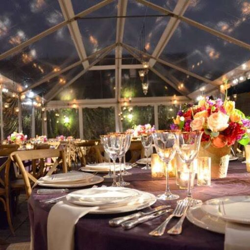 Pin-Spots are highlighting the table centerpieces on diner tables under a clear-top tent at The Foundry.