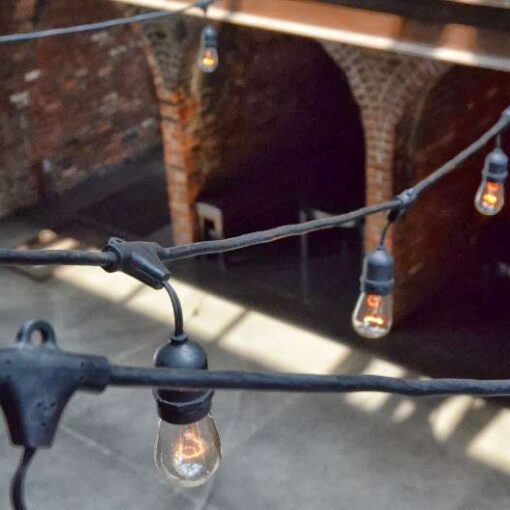 Warm white Bistro lights hanging across the mezzanine level for a wedding in the main room at The Foundry.