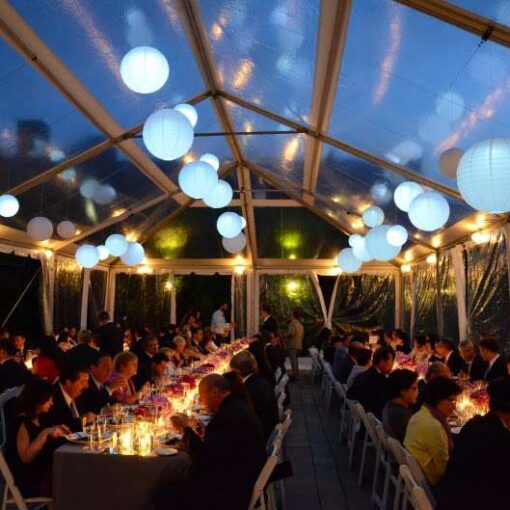 Paper Lanterns with decorative LED lights inside are hanging under a clear-top tent for a wedding in the rear courtyard at The Foundry.