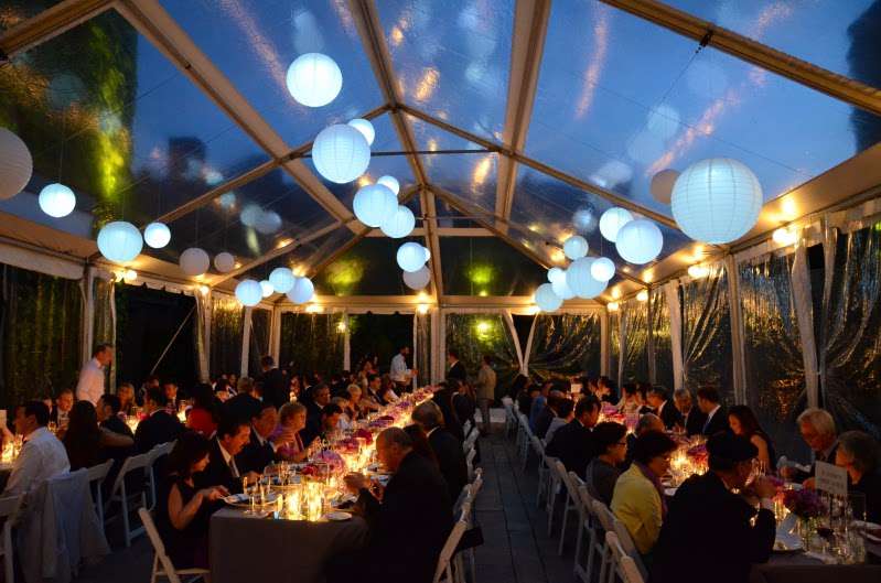 Paper Lanterns with decorative LED lights inside are hanging under a clear-top tent for a wedding in the rear courtyard at The Foundry.
