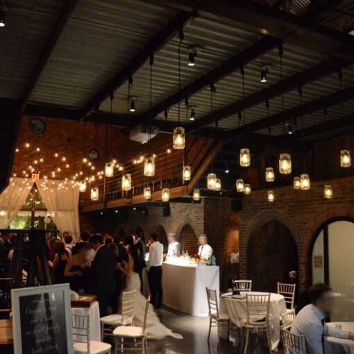 Warm white String Lights and Pendant Lamps each with a Mason Jar hanging in the main room for a wedding at The Foundry.