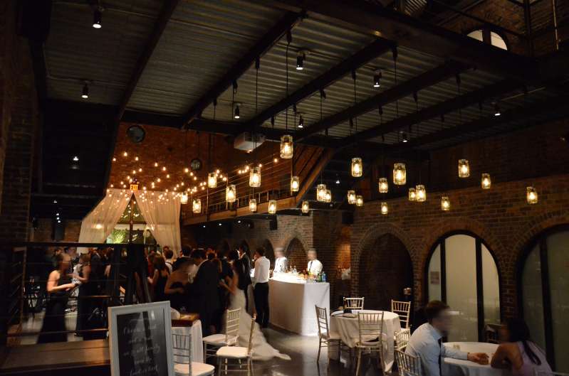 Warm white String Lights and Pendant Lamps each with a Mason Jar hanging in the main room for a wedding at The Foundry.
