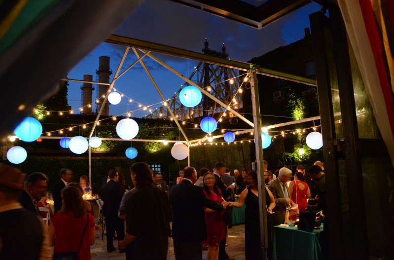 String lights with paper lanterns are hanging under a tent frame for a wedding in the rear courtyard at The Foundry.