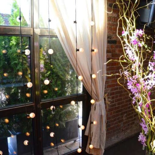 Warm white string lights hanging across the mezzanine level and String Lights hanging vertically against the rear courtyard doors for a wedding at The Foundry.