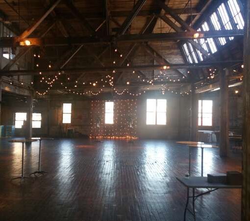 String Lights hanging vertically as a backdrop behind ceremony and overhead for a wedding at The Greenpoint Loft located in Brooklyn, New York.