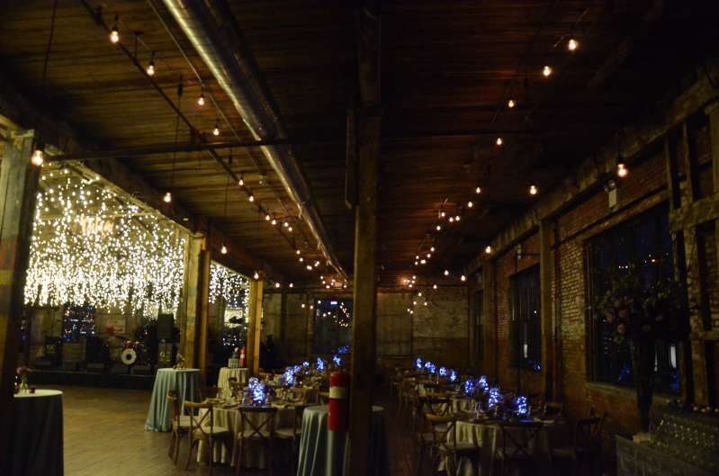 Warm White String Lights are hanging in parallel lines under the lower ceiling area on the main floor for a Bat Mitzvah at The Greenpoint Loft.