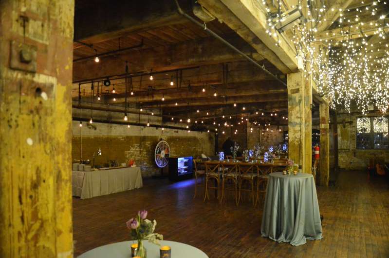 Warm White String Lights are hanging in parallel lines under the lower ceiling area on the main floor for a Bat Mitzvah at The Greenpoint Loft.
