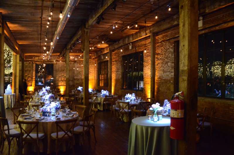 Warm White String Lights are hanging in parallel lines under the lower ceiling area on the main floor for a Bat Mitzvah at The Greenpoint Loft with Up-Lights.