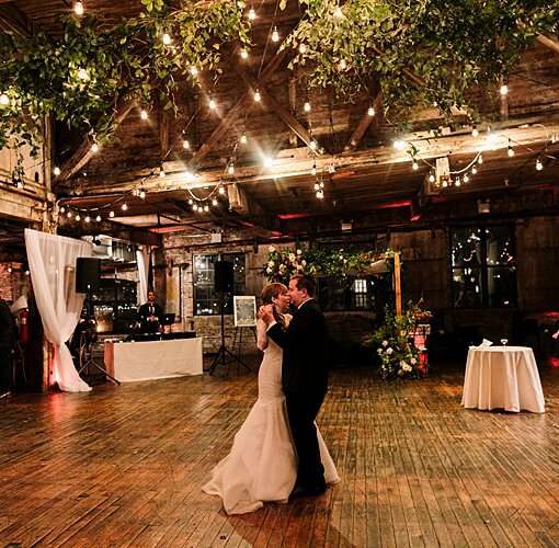 String Lights hanging in a circular pattern between the six center columns for a wedding in the main room at The Greenpoint Loft.