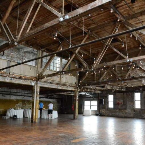 Warm White String Lights hanging in a zigzagging pattern between the six center columns for a wedding in the main room at The Greenpoint Loft.