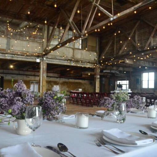 Warm White String Lights hanging in a zigzagging pattern between the six center columns for a wedding in the main room at The Greenpoint Loft.