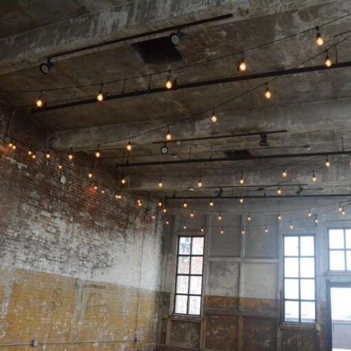 Warm White String Lights hanging in a zigzagging pattern on the mezzanine level for a wedding at The Greenpoint Loft.
