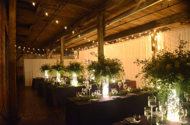 Warm White String Lights are hanging in a zigzagging pattern under the lower ceiling area on the main floor for a wedding at The Greenpoint Loft.