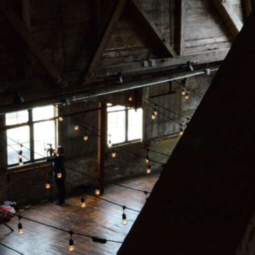 String lights are hanging in a zigzagging pattern for a wedding in the main room at The Greenpoint Loft.