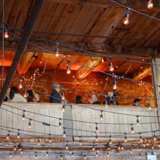 String lights are hanging in a zigzagging pattern for a wedding in the main room at The Greenpoint Loft.