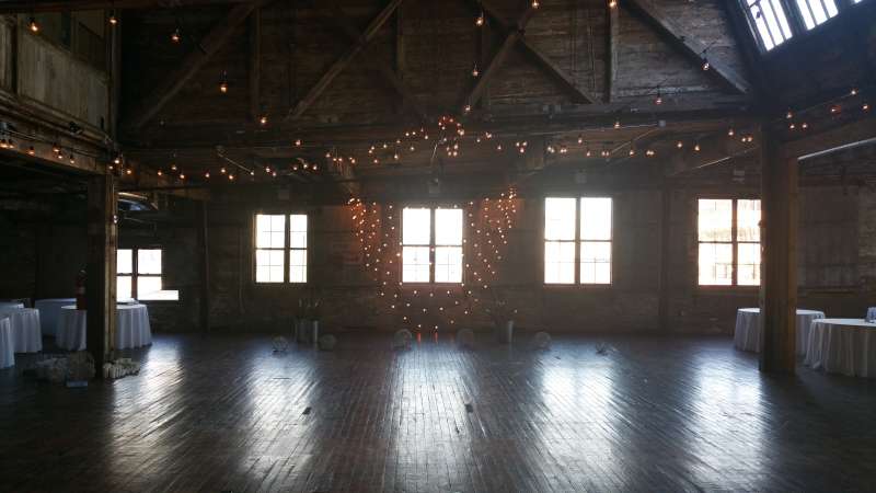 String Lights hanging against a wall with multiple swoops along with String Lights hanging overhead in a V-shaped pattern for a wedding at The Greenpoint Loft.