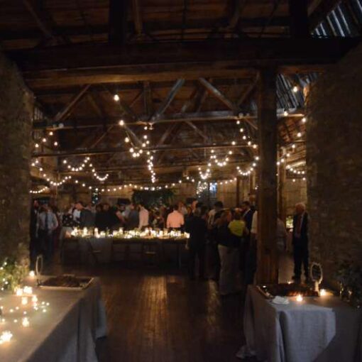 Warm White String Lights hanging in parallel lines between the six center columns for a wedding in the main room at The Greenpoint Loft.