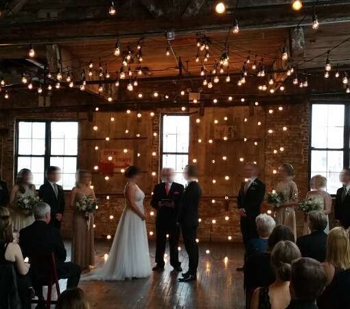 String Lights hanging against a wall in vertical lines for a wedding at The Greenpoint Loft.