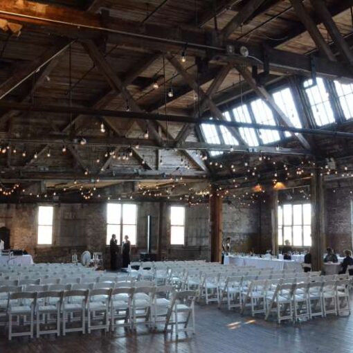 Warm White String Lights hanging in a zigzagging pattern between the six center columns for a wedding in the main room at The Greenpoint Loft.