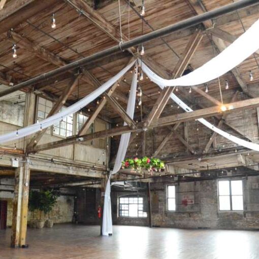 Sheer curtains hanging in an X-Shaped pattern under the high ceiling area of the main floor with String Lights.