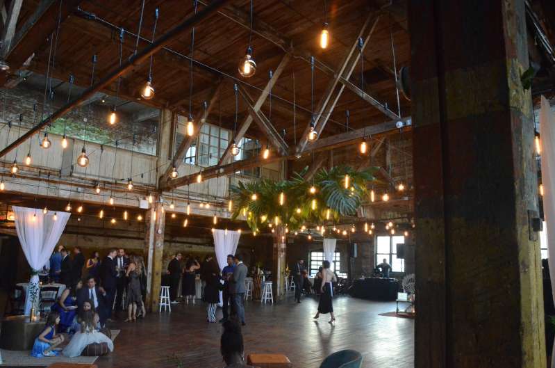 Pendant Lamps with vintage antique Edison bulbs hanging between the six center columns for a wedding in the main room with White Sheer curtains at The Greenpoint Loft.