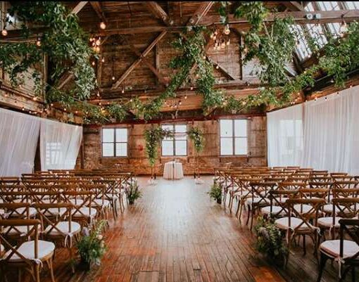 String Lights hanging in a zigzagging pattern for a wedding in the main room at The Greenpoint Loft with White Sheer curtains to partition the ceremony area between the six center columns.