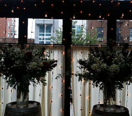 A vertical curtain of string lights hanging against the windows for a wedding in the atrium at The Brooklyn Winery.